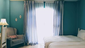Un dormitorio con cama, una silla, una lámpara y cortinas.