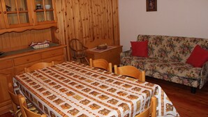 Une pièce chaleureuse avec un meuble en bois, un canapé à motifs floraux et une table à manger avec des chaises.