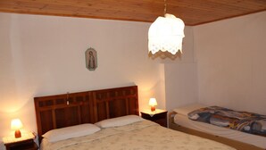 Une chambre à coucher avec un grand lit, un lit plus petit, une tête de lit en bois, des lampes de chevet et un luminaire suspendu.