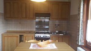 A kitchen with wooden cabinets, a stove, and a sink. - Casa Rosina 6 (Val di Zoldo)