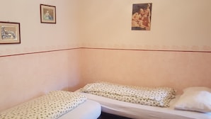 A small, simple room with two single beds, a wooden headboard, and a wall with three framed pictures. - Casa Rosina 6 (Val di Zoldo)