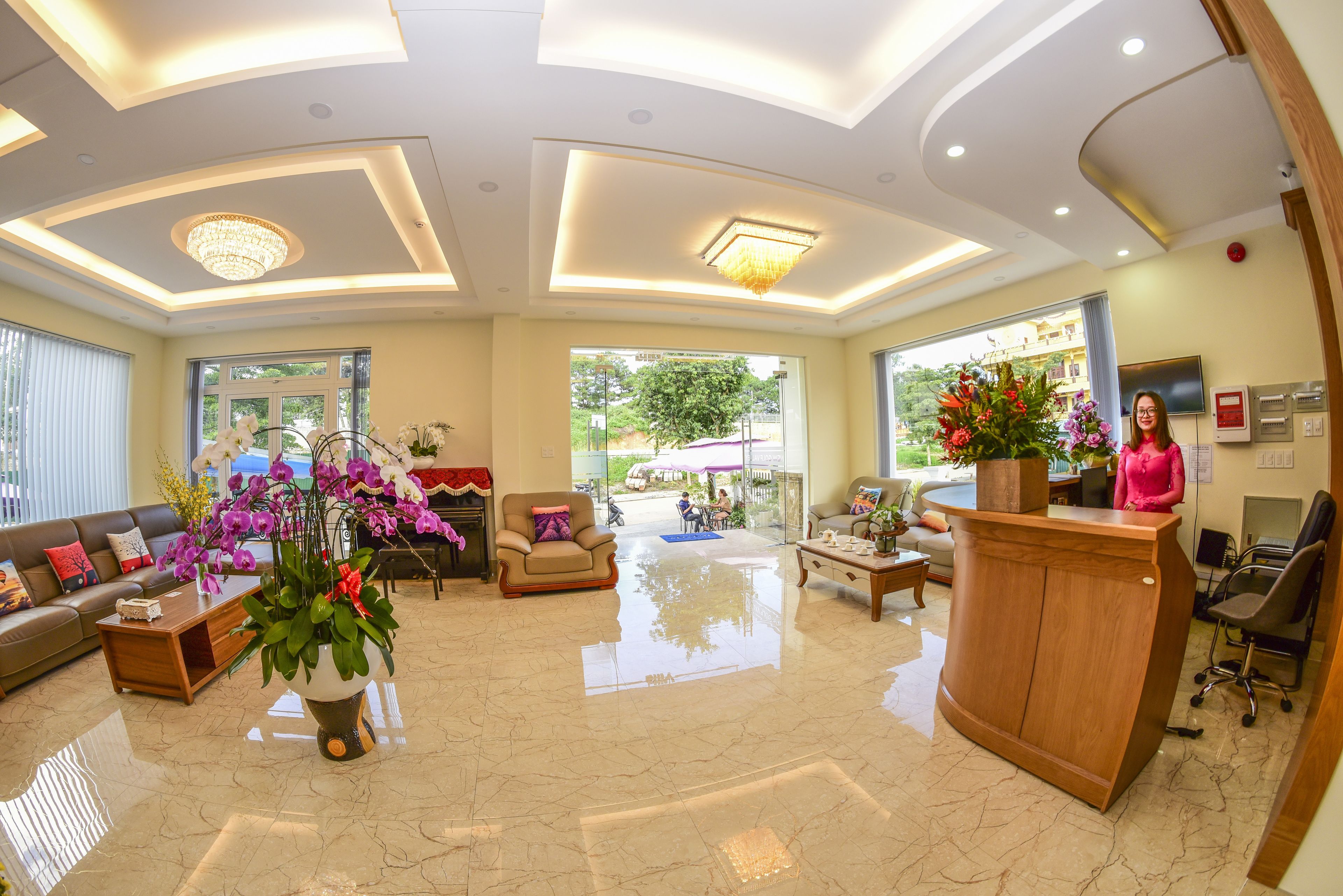 A spacious lobby with a reception desk, seating area, and large windows offering a view of the outdoors.