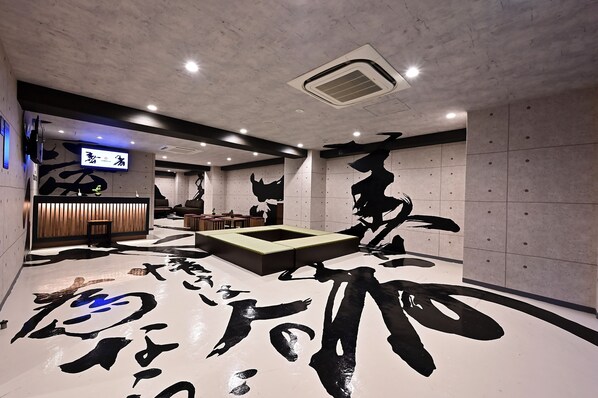 A modern interior with a reception area, seating, and a unique black and white floor design. - Hotel Tomariya Ueno - Hostel (Tokyo)