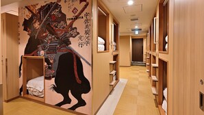 A hotel corridor with wooden lockers and a mural of a samurai on the wall. - Hotel Tomariya Ueno - Hostel (Tokyo)