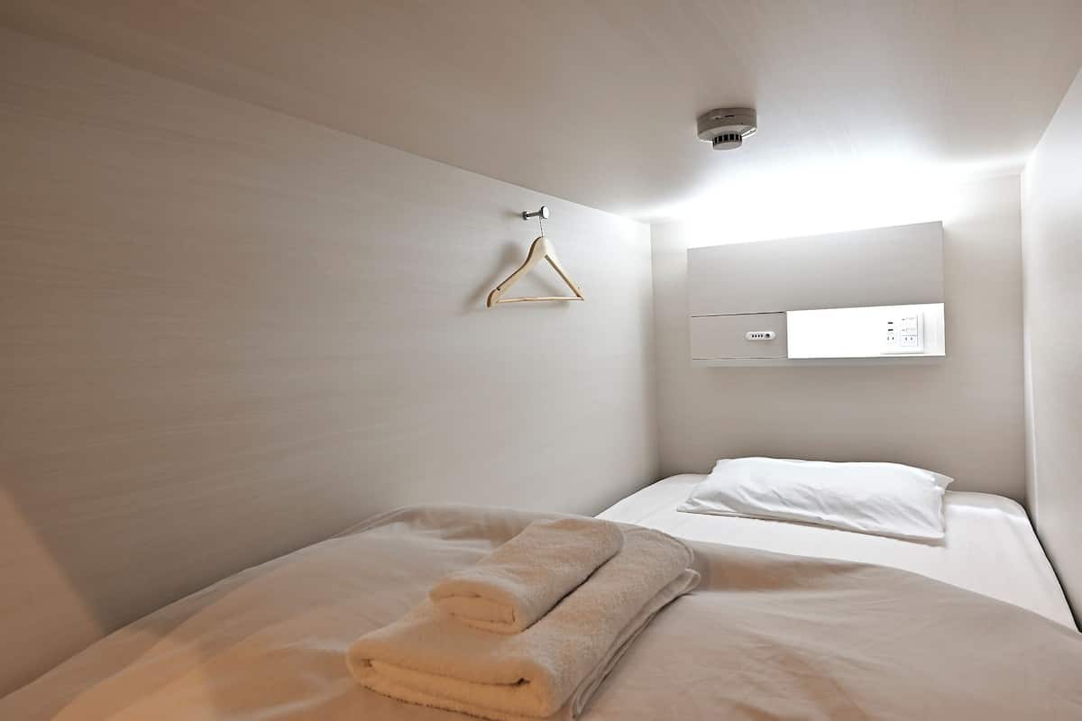 Ett hotellrum med två sängar, ett vägguttag och en hängande lampa.