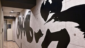 A hallway with a modern design, featuring a large abstract wall art and a wooden floor. - Hotel Tomariya Ueno - Hostel (Tokyo)
