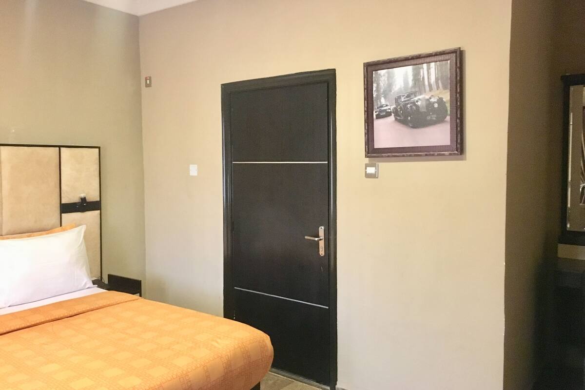 Une chambre d’hôtel avec un lit, une porte et un tableau encadré au mur.