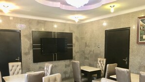 A restaurant with marble walls, a flat-screen TV mounted above a table, and leather chairs. - Elicris Hotel (Lagos)