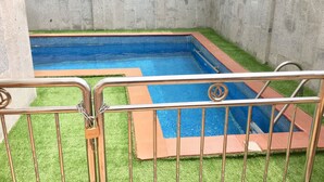 A swimming pool with a 'POOL RULES' sign, surrounded by a metal fence and artificial grass. - Elicris Hotel (Lagos)