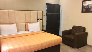 A hotel room with a bed, a brown armchair, and a wardrobe. - Elicris Hotel (Lagos)