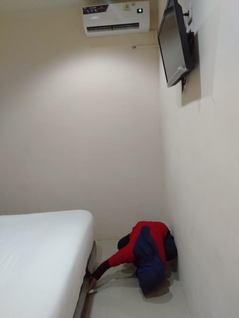 Une petite pièce comprenant un lit, un appareil de climatisation et un téléviseur fixé au mur.