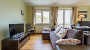 A living room with a TV, sofa, and dining table. - Apartament Cichy - Apartamenty 5d (Swieradow-Zdroj)