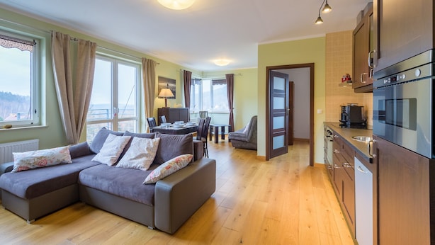 A modern living room with a sectional sofa, a dining area, and a kitchen with stainless steel appliances. - Apartament Cichy - Apartamenty 5d (Swieradow-Zdroj)