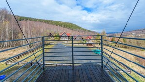 A wooden deck with metal railings overlooking a rural landscape with houses and a road. - Apartament Cichy - Apartamenty 5d (Swieradow-Zdroj)