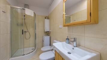 A bathroom with a glass-enclosed shower, a toilet, a sink, and a mirror.