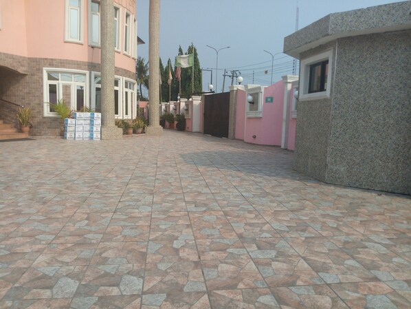 Un patio con piso de baldosas, una pila de cajas y un edificio de fachada rosa.