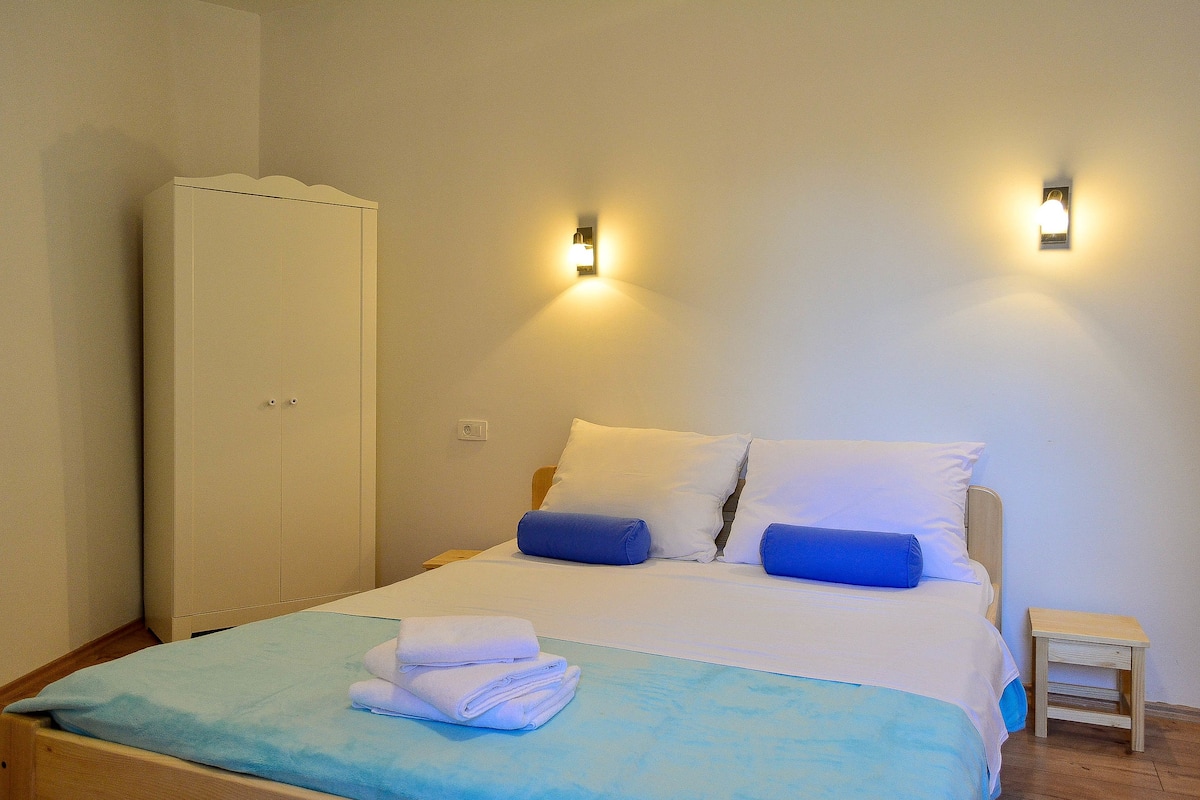 Une chambre à coucher avec un lit, des oreillers, une armoire et des lampes fixées au mur.