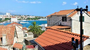 A coastal town with terracotta-roofed buildings, a marina, and a clear blue sky. - Golden B&B (Split)