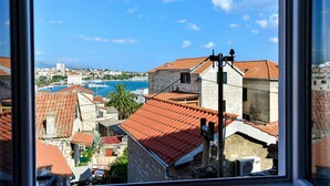 A coastal cityscape with terracotta-roofed buildings, a clear blue sky, and a view of the sea. - Golden B&B (Split)