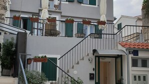 A two-story building with a balcony, outdoor seating, and a staircase leading to the entrance. - Golden B&B (Split)