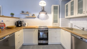 Een moderne keuken met witte kasten, een roestvrijstalen oven en een houten aanrecht.