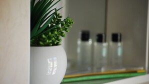 Un pot en céramique blanche contenant des plantes vertes, posé sur une étagère blanche.