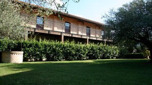 Un bâtiment à deux étages doté d’un balcon, entouré d’un espace verdoyant bien entretenu.