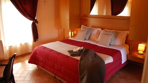 Une chambre d’hôtel avec un grand lit, une tête de lit en bois, deux tables de chevet avec des lampes, une chaise et une fenêtre avec des rideaux.