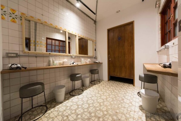 A restroom with a tiled floor, a wooden door, a mirror, and three stools. - 158 Hostel (Tainan)