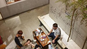 A spacious outdoor area with a wooden ceiling, a dining table with chairs, and a seating bench. - 158 Hostel (Tainan)