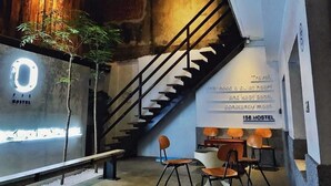 A hostel interior with a staircase, seating area, and a wall with a circular sign and text. - 158 Hostel (Tainan)
