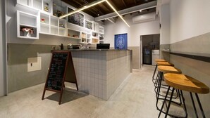 A modern kitchen with white cabinetry, a chalkboard menu, and bar stools. - 158 Hostel (Tainan)