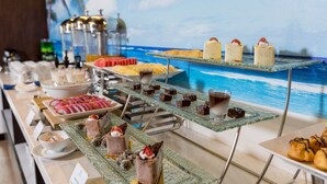 A buffet with various desserts and pastries, including cakes, cookies, and chocolate treats, displayed on glass stands. - CN Palace Boutique Hotel & Spa (Da Nang)
