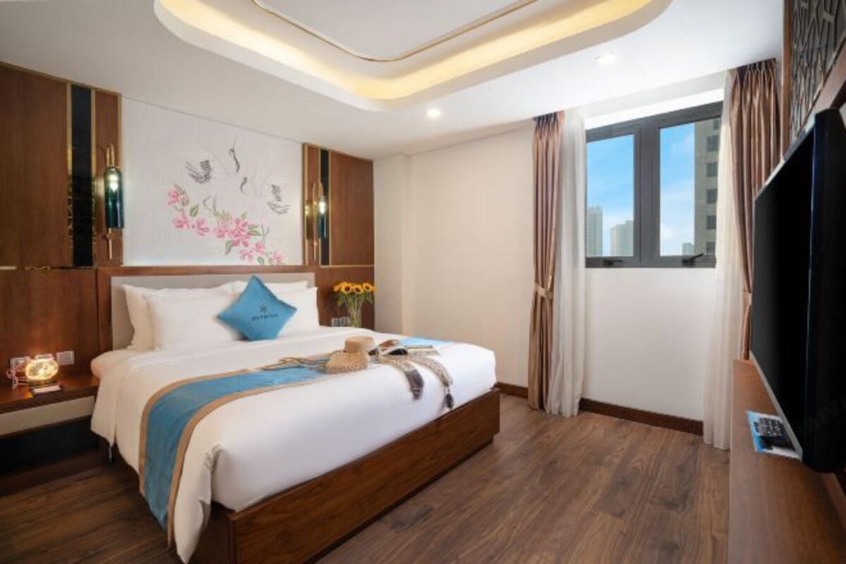 A modern hotel room with a large bed, a flat-screen TV, and a city view.