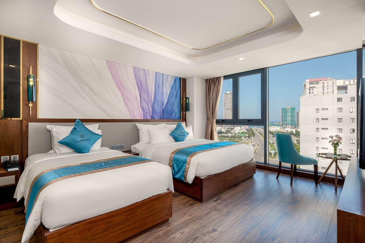 A hotel room with two beds, a view of the city, and a modern design.