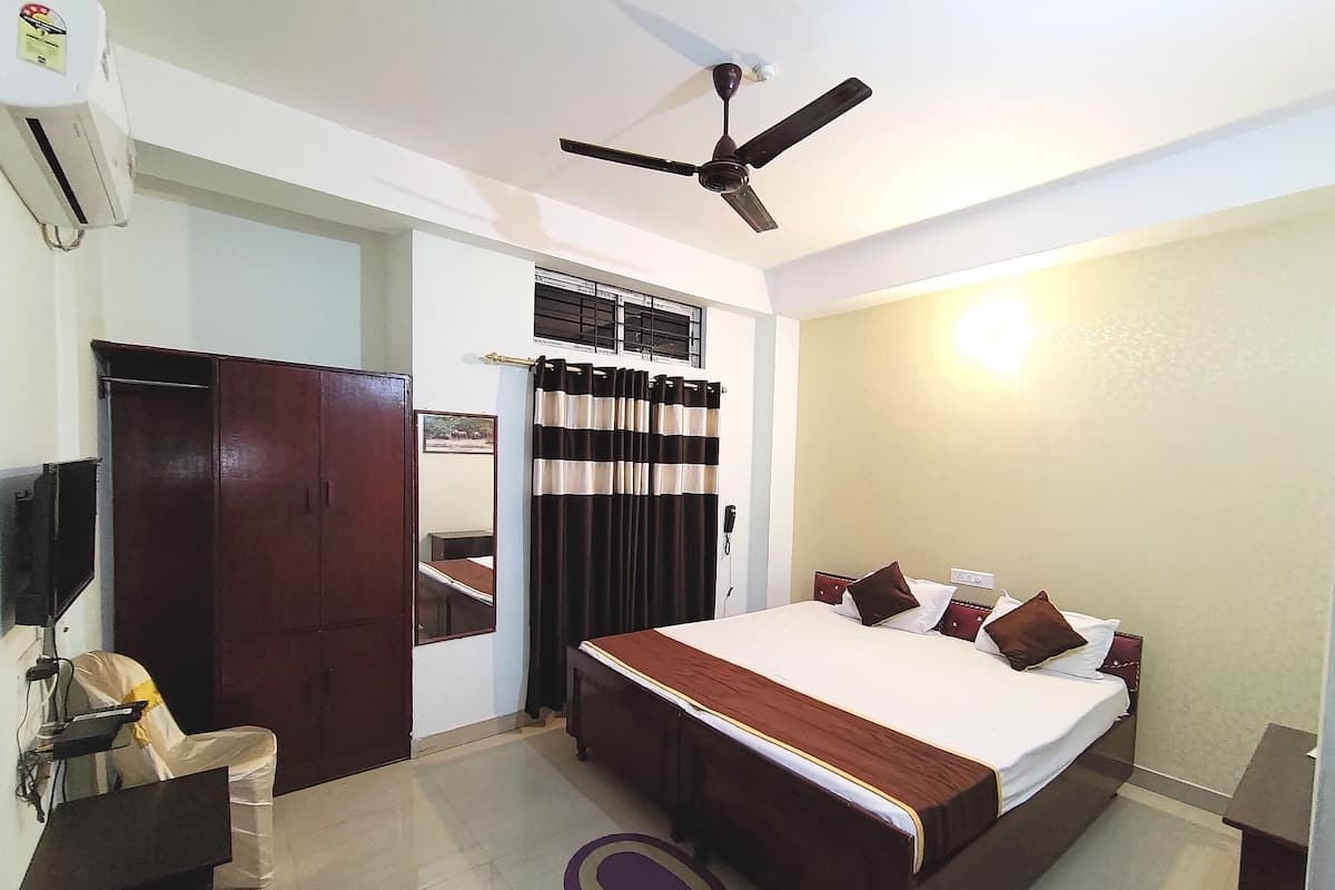 A bedroom with a bed, a ceiling fan, a wardrobe, a desk, and a chair.