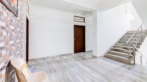 Ein geräumiger Korridor mit Marmorboden, einer Holztür und einer Treppe mit Metallgeländern.