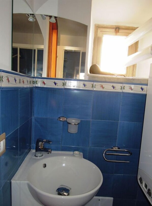 A bathroom with a white sink, blue tiles, and a mirror above it. - Sole e Mare (Salerno)