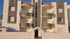 A modern multi-story building with balconies, a central entrance, and a symmetrical facade. - Residence Stern (Hammam Al Agzaz)