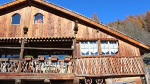 A wooden chalet with a balcony, large windows, and a wooden fence. - Chalet Fiore (Val di Zoldo)