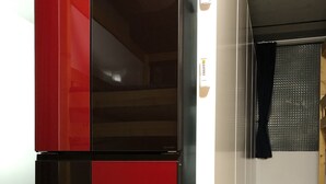 A modern kitchen with a black and red refrigerator, white cabinets, and a wooden ceiling. - Hotel Adonis - Hostel (Tokyo)