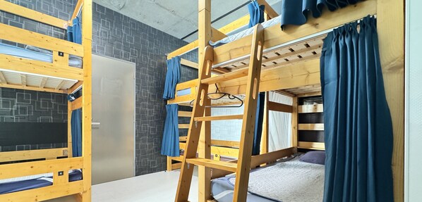 A bunk bed room with a ladder, a grey door, and a patterned wall.