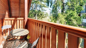 A wooden balcony with a table and chairs, overlooking a forested area. - Apartament z Sauną pod Świerkami - Apartamenty 5d (Karpacz)