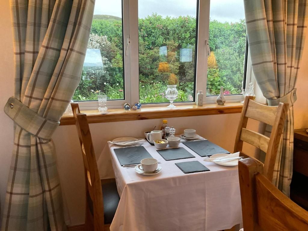A dining table set for two with a view of greenery outside.