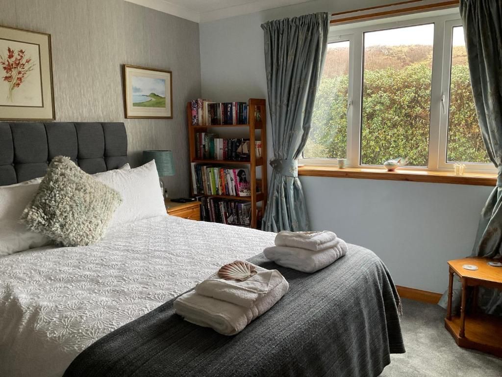 A bedroom with a bed, a bookshelf, and a window with curtains.