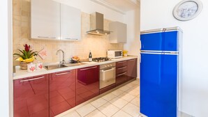 Una cocina con estufa a gas, horno, microondas y un refrigerador azul.