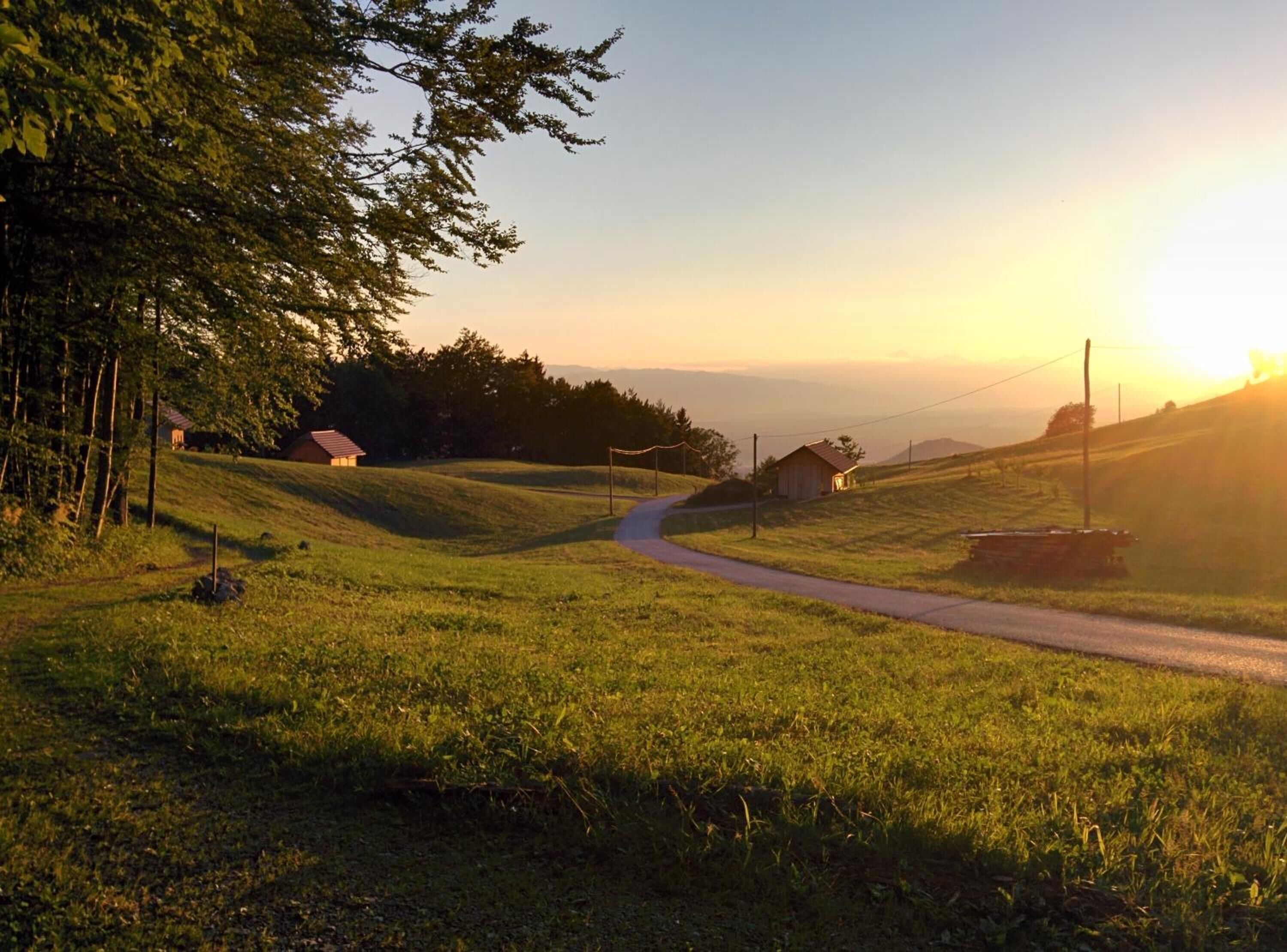 Un paysage rural avec une route sinueuse, une petite maison et une grange.
