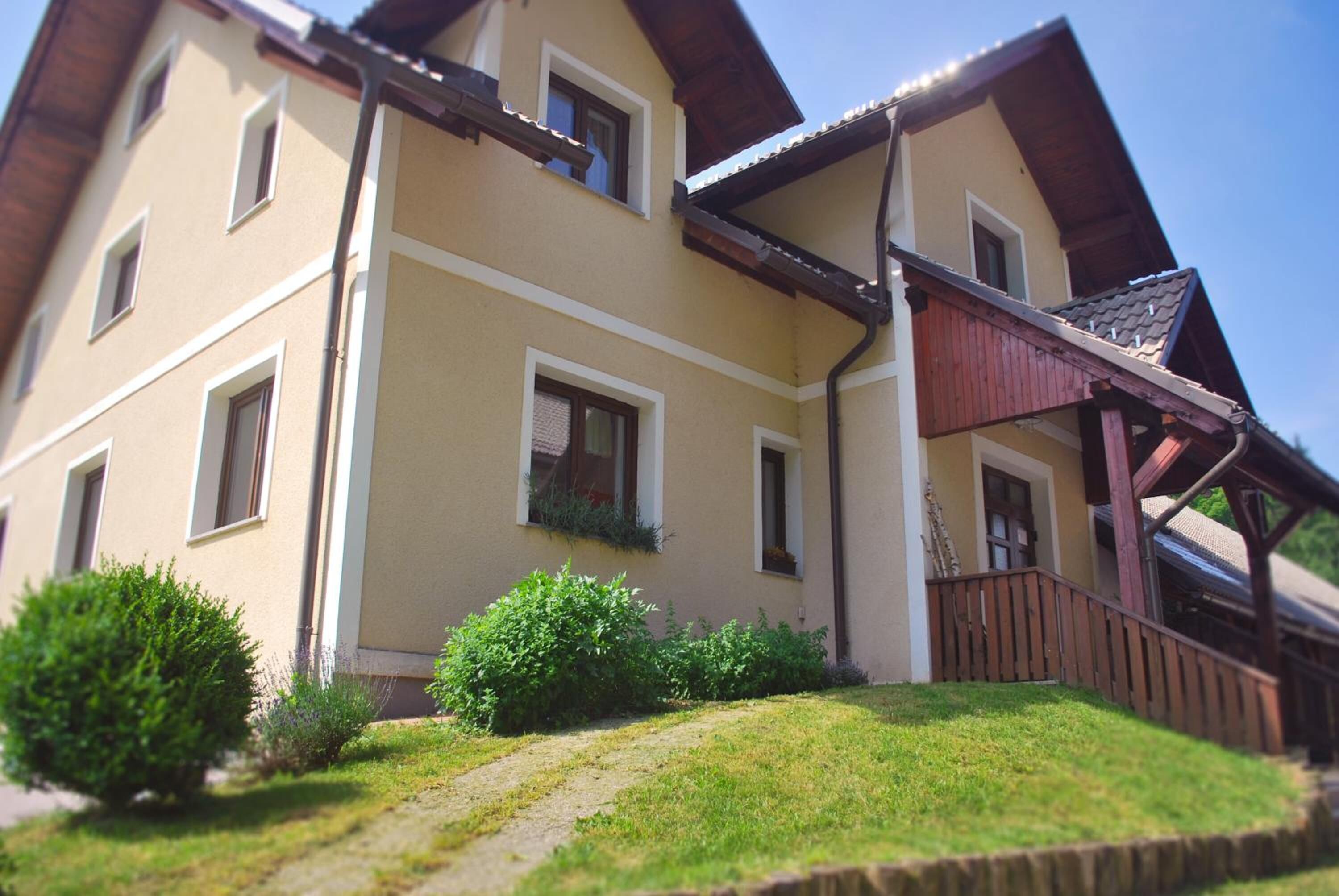 A two-story building with a sloped roof, multiple windows, and a wooden balcony.