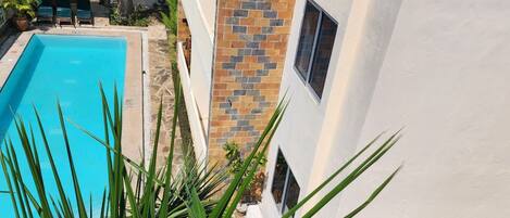 Una piscina junto a un edificio de fachada de piedra y una ventana.