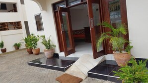 A building entrance with a wooden door, potted plants, and a tiled floor. - Pendo Villas Diani (Diani Beach)